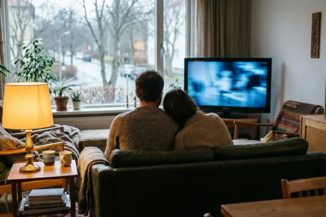 Katsojat seuraavat jännityssarjaa kotona.